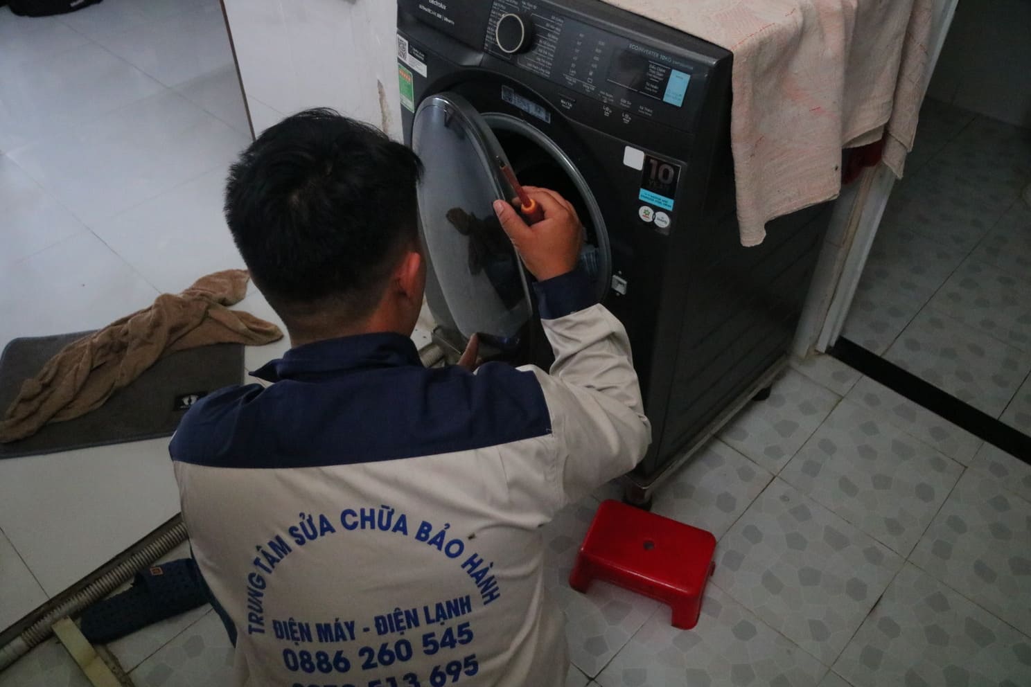 Kỹ thuật viên bên máy giặt cửa trước sau khi sửa xong